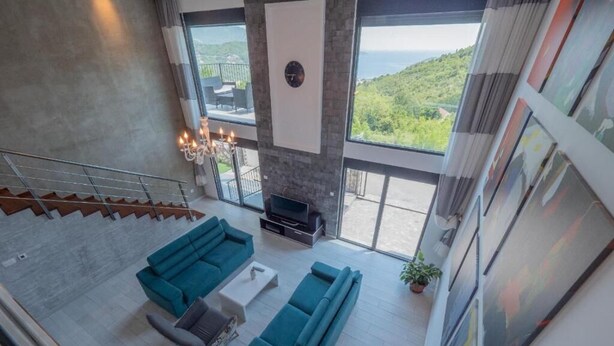A spacious living area with a large sofa set, a fireplace, and a view of a mountainous landscape through large windows. - Seaview Villa with pool Hanja (Podostrog)