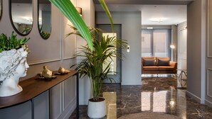 A modern interior with a marble floor, a potted plant, a sofa, and a console table with decorative items. - Grand Terrace Suite/105m² - Spacious outdoor living area (Argostoli)