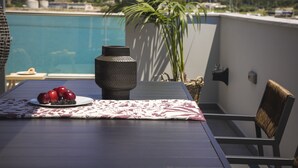 A dining table with a plate of fruit, a vase, and a chair. - Grand Terrace Suite/105m² - Spacious outdoor living area (Argostoli)