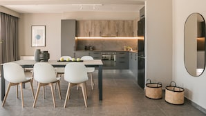 A modern kitchen with grey cabinets, a dining table with chairs, and a large mirror. - Luxury Living Suite-2 bedroom-Sea View/115m² (Argostoli)