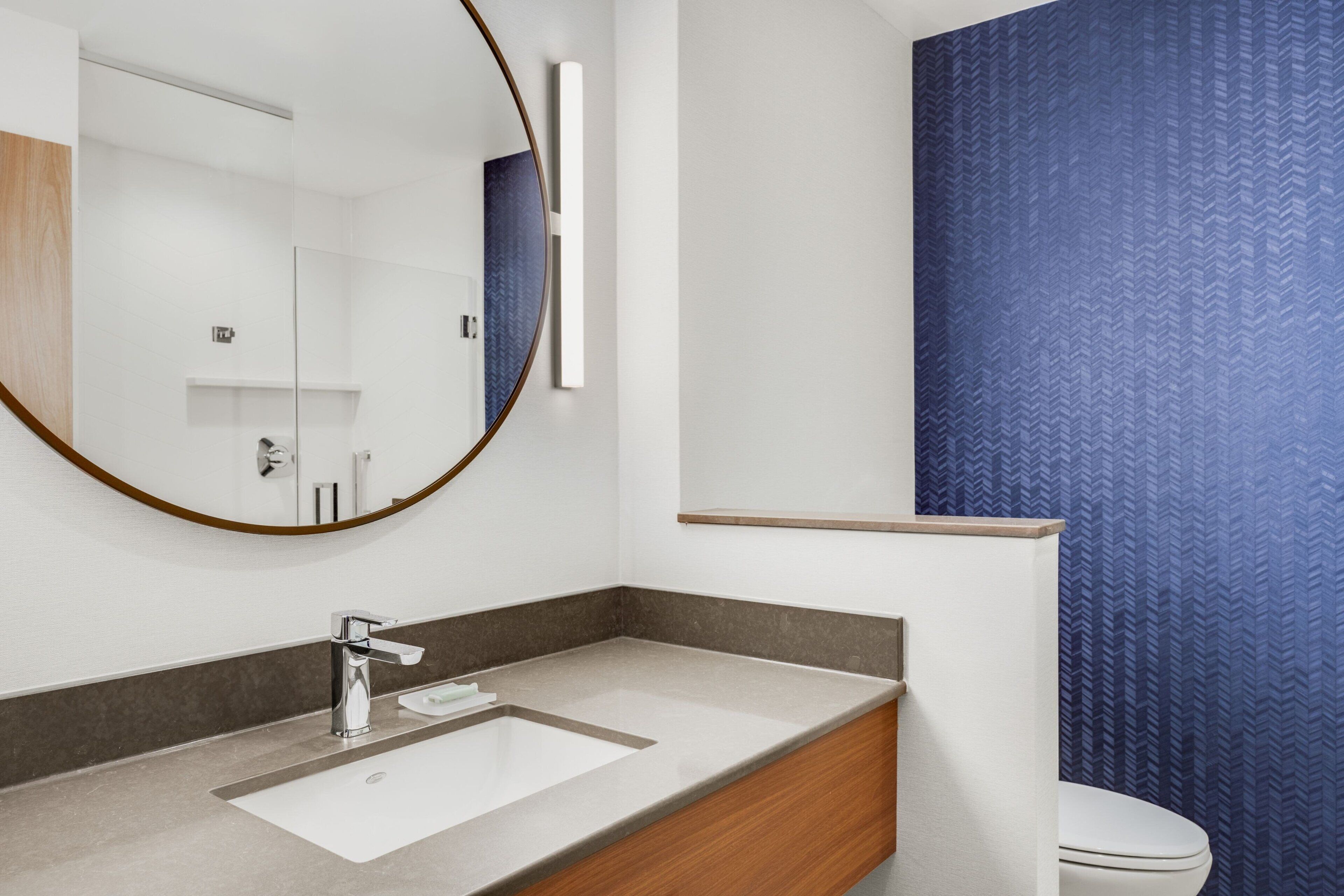 Un bagno moderno con uno specchio grande, un lavandino e un water.
