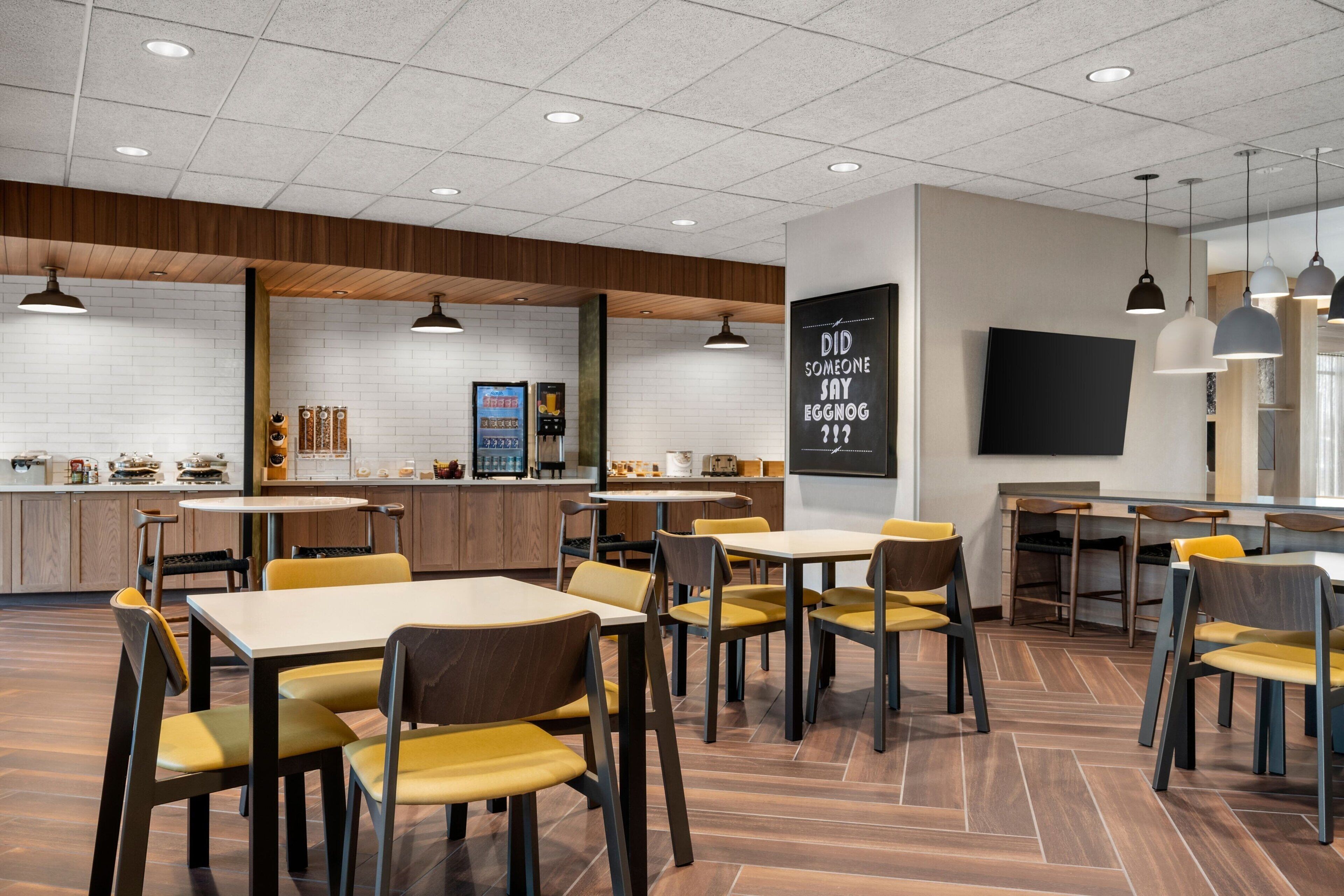 Un restaurant moderne au design épuré et minimaliste, agrémenté d’éléments en bois et offrant différents types de sièges.