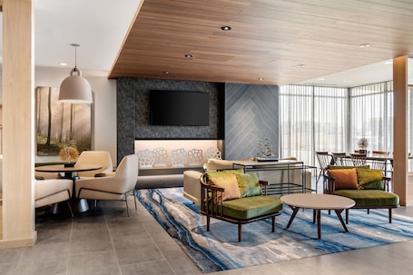 A modern living room with a sofa, armchairs, a coffee table, and a TV mounted on the wall.