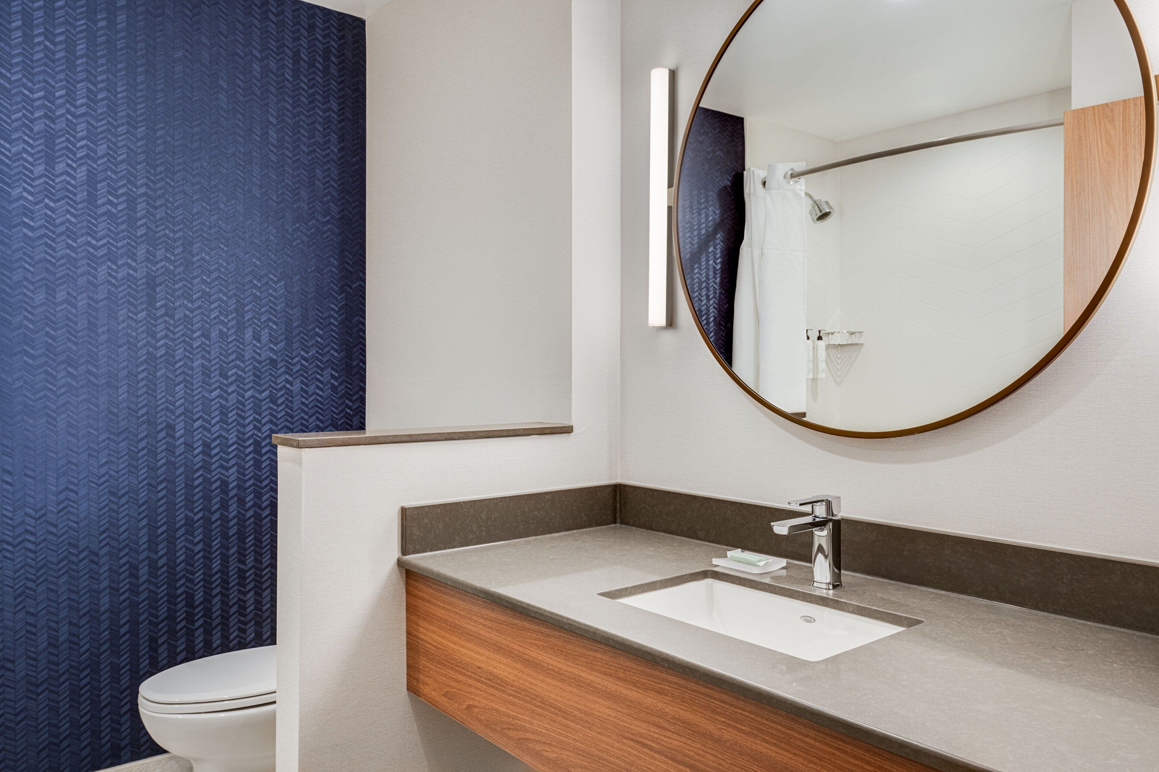 A modern bathroom with a wooden vanity, a large mirror, and a white toilet.