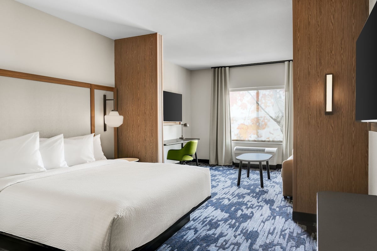 Een hotelkamer met een groot bed, een bureau, een stoel en een raam met gordijnen.
