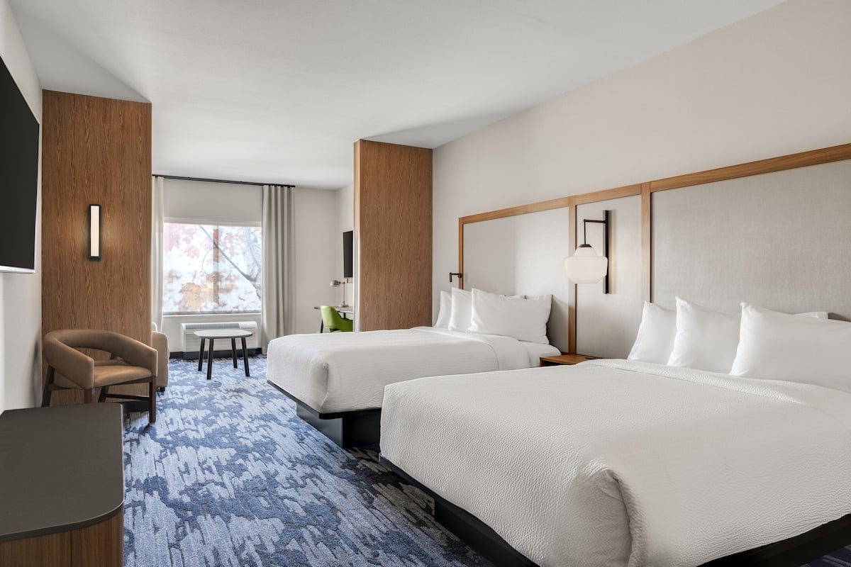 Een hotelkamer met twee bedden, een bureau en een stoel.