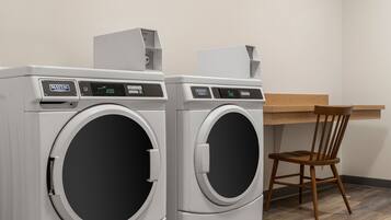 Two Maytag front-loading washing machines in a room with a wooden chair and a desk.