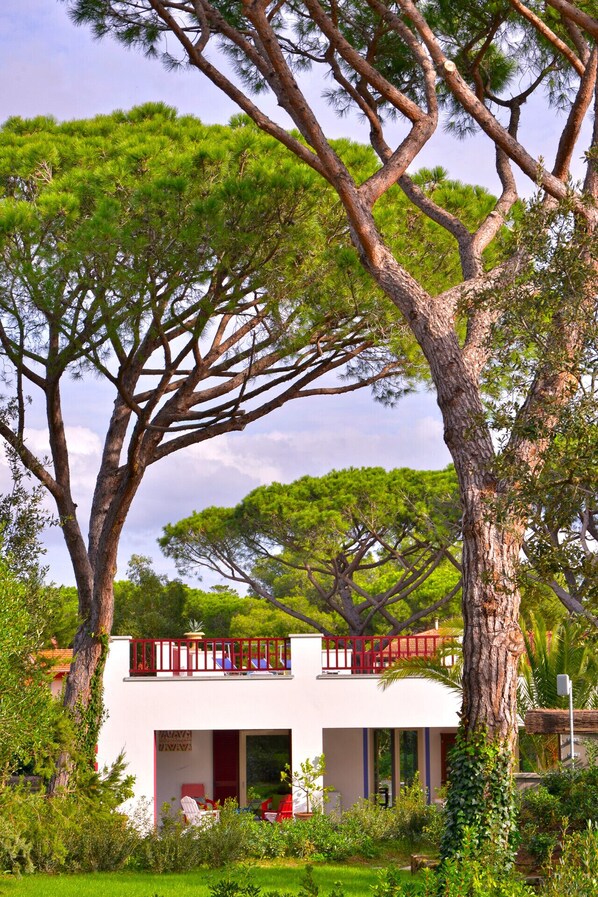 A modern villa with a white exterior, large windows, and a red balcony.