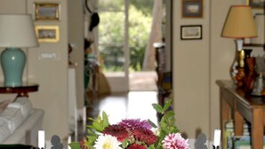 A room with a floral arrangement on a table, a lamp, and framed pictures on the walls. - Villa Gioconda - Homelike Villas (Bibbona)