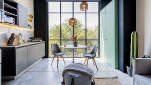 A modern kitchen with a dining area, large windows, and a cactus plant. - w* | Glorious Loft w/ Beautiful Deco in Roma Norte (Ciudad de México)