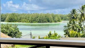 Vista de una playa tropical con aguas turquesas cristalinas, abundante follaje verde y un cielo nublado.