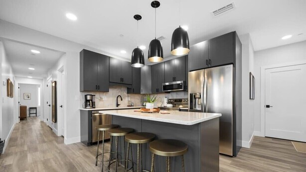 A modern kitchen with dark cabinets, stainless steel appliances, and a central island with stools. - Slabtown 203 Downtown Location with Two Balconies! (Traverse City)