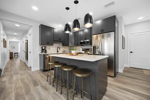 A modern kitchen with dark cabinets, stainless steel appliances, and a central island with stools. - Slabtown 203 Downtown Location with Two Balconies! (Traverse City)