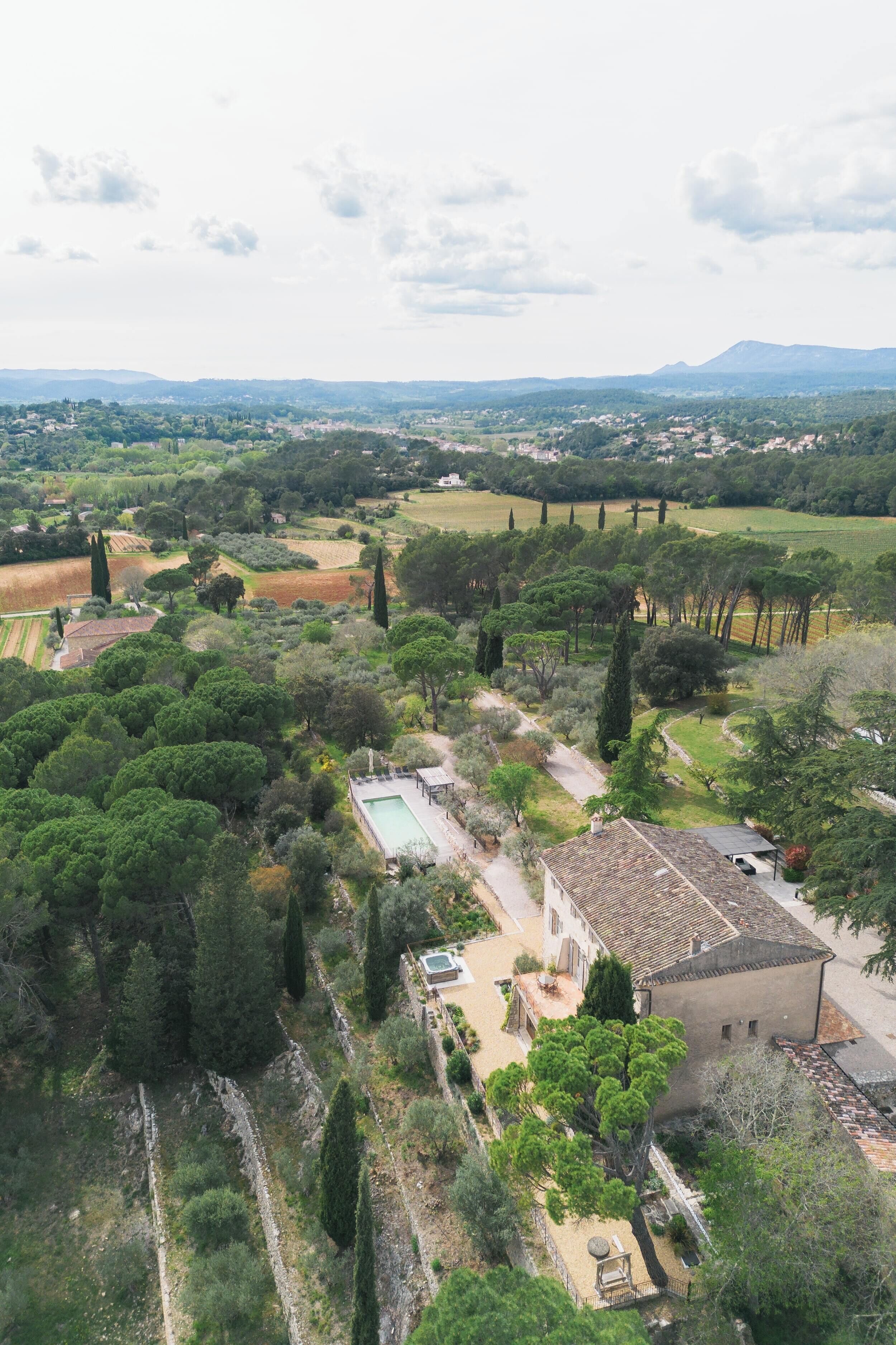 An aerial view of a rural property with a large garden, a swimming pool, and a traditional building.