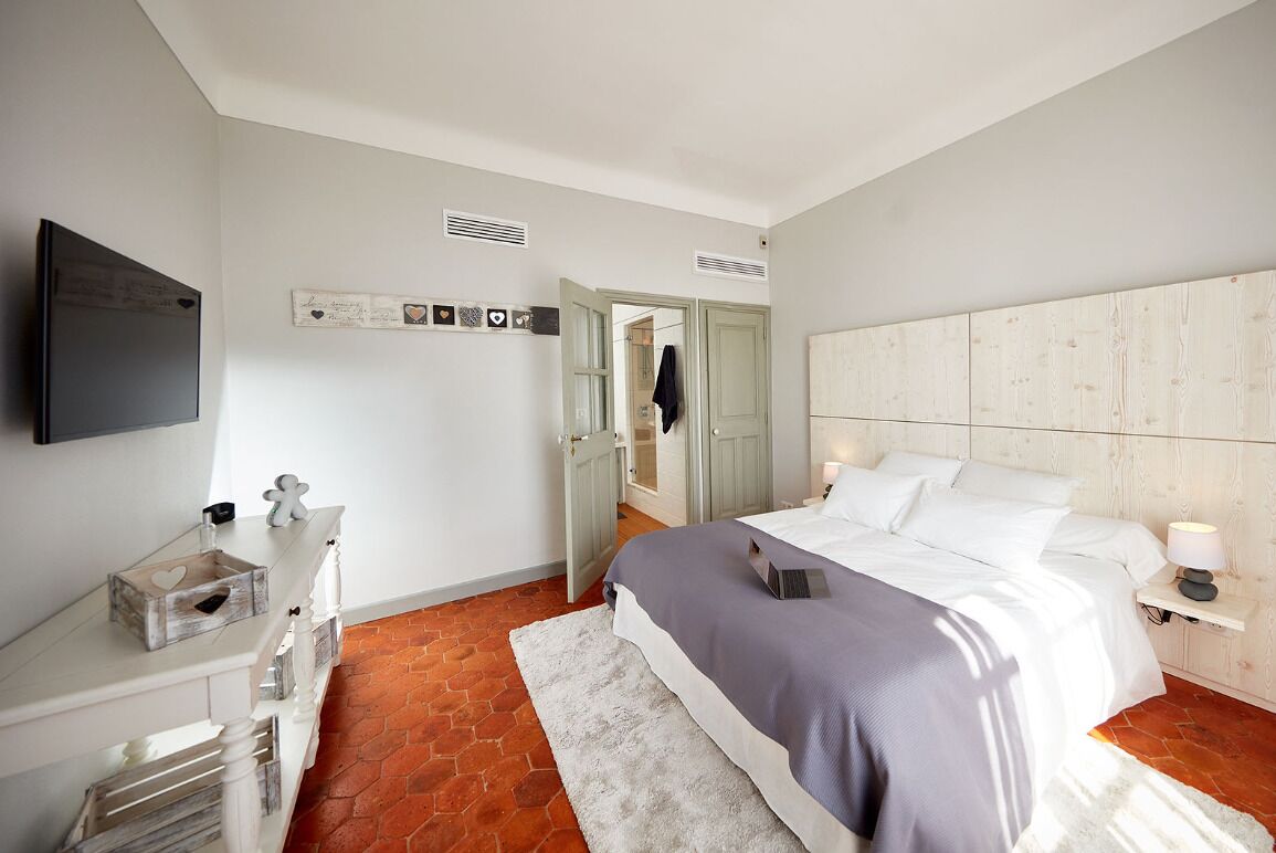 A bedroom with a bed, bedside table, and a television on the wall.