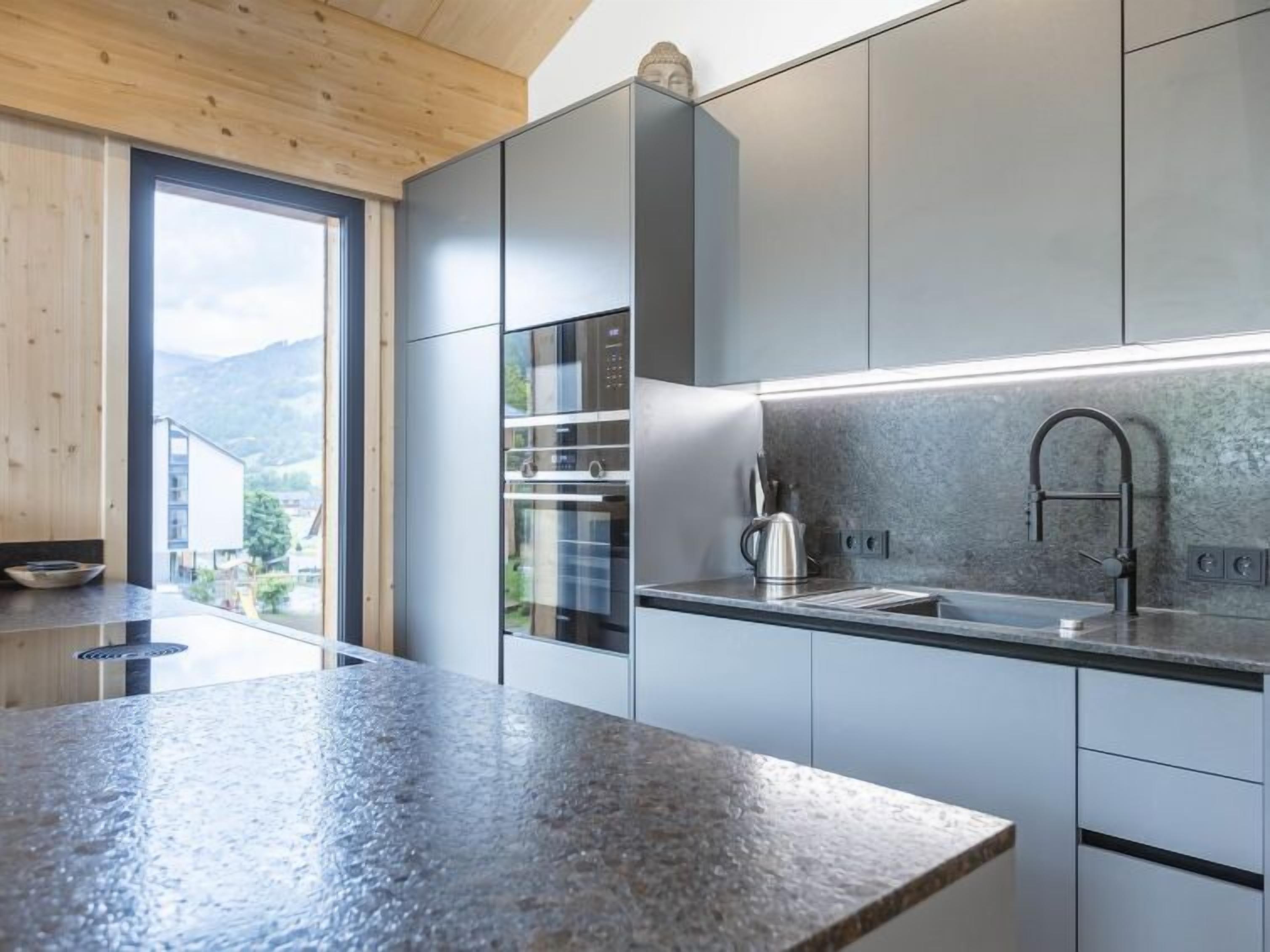 Una cocina moderna con encimera de granito, electrodomésticos de acero inoxidable y vistas al exterior.