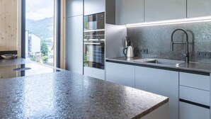 A modern kitchen with a granite countertop, stainless steel appliances, and a view of the outdoors. - #4a mit Sauna & Pool by Interhome (Sankt Georgen am Kreischberg)