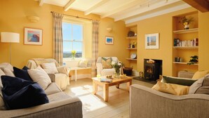A cozy living room with a fireplace, comfortable seating, and a bookshelf. - Higher Roskestal (Penzance)