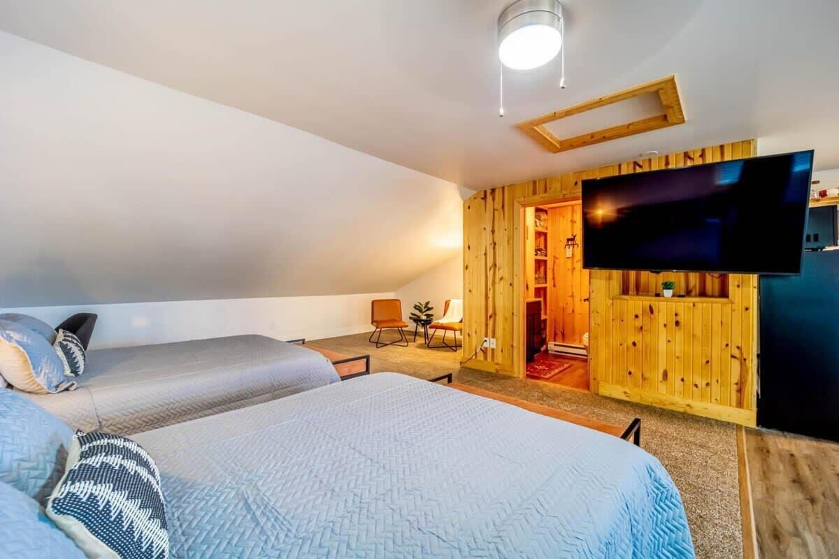 A bedroom with two beds, a television, and a wooden wall.
