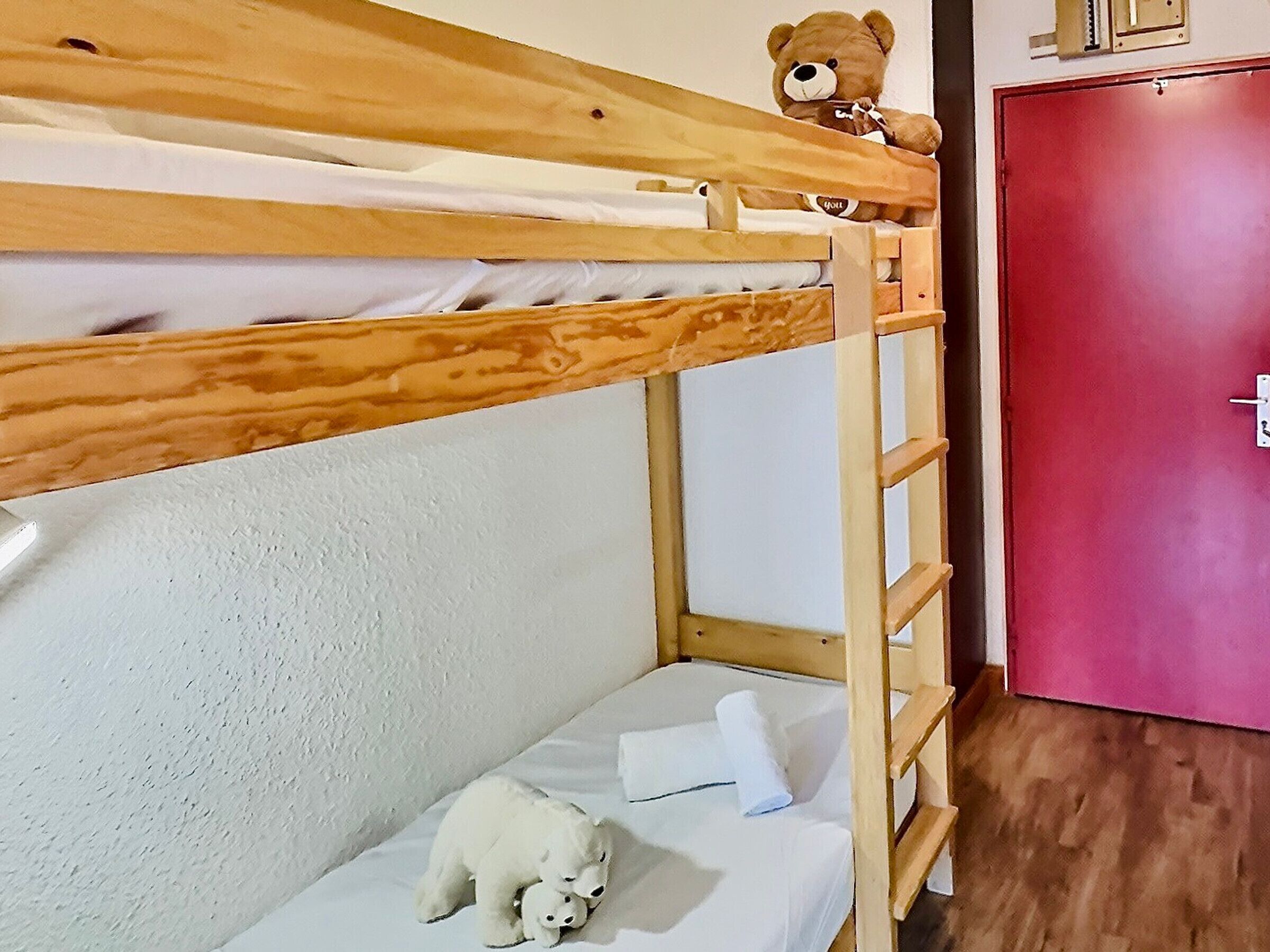 A bunk bed with a teddy bear on the top bunk and a polar bear plush toy on the bottom bunk.