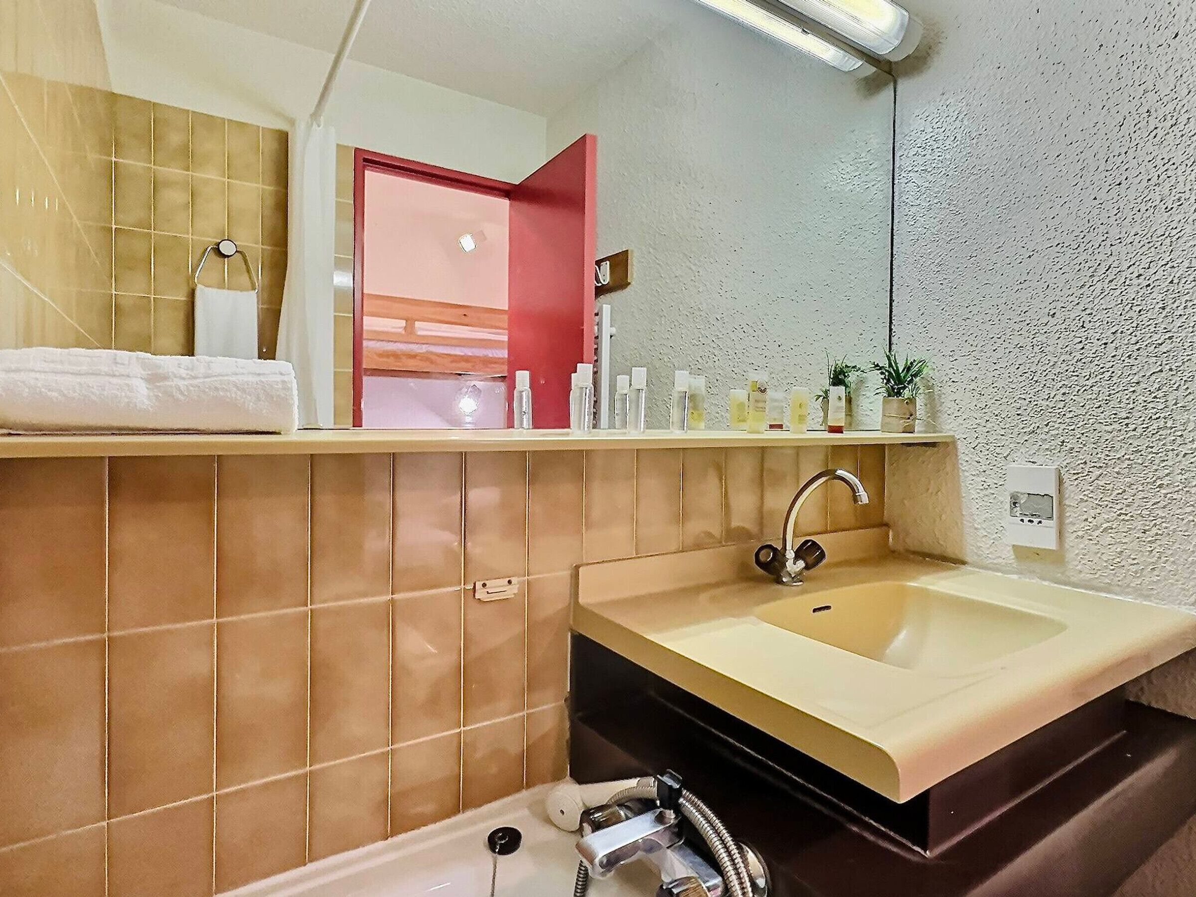 Een badkamer met een beige wastafel, een spiegel en een handdoekhouder.