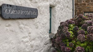 A sign reading "Corner Cottage" on a white building with a small window. - Corner Cottage (Penzance)