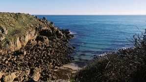 A coastal landscape with rocky terrain and a clear view of the sea. - Cove Cottage (Penzance)