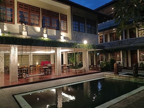A courtyard with a pool, outdoor seating, and a building with traditional architecture. - Catur Adi Putra Hotel (Denpasar)