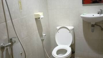 A small, tiled bathroom with a toilet, a sink, and a shower.