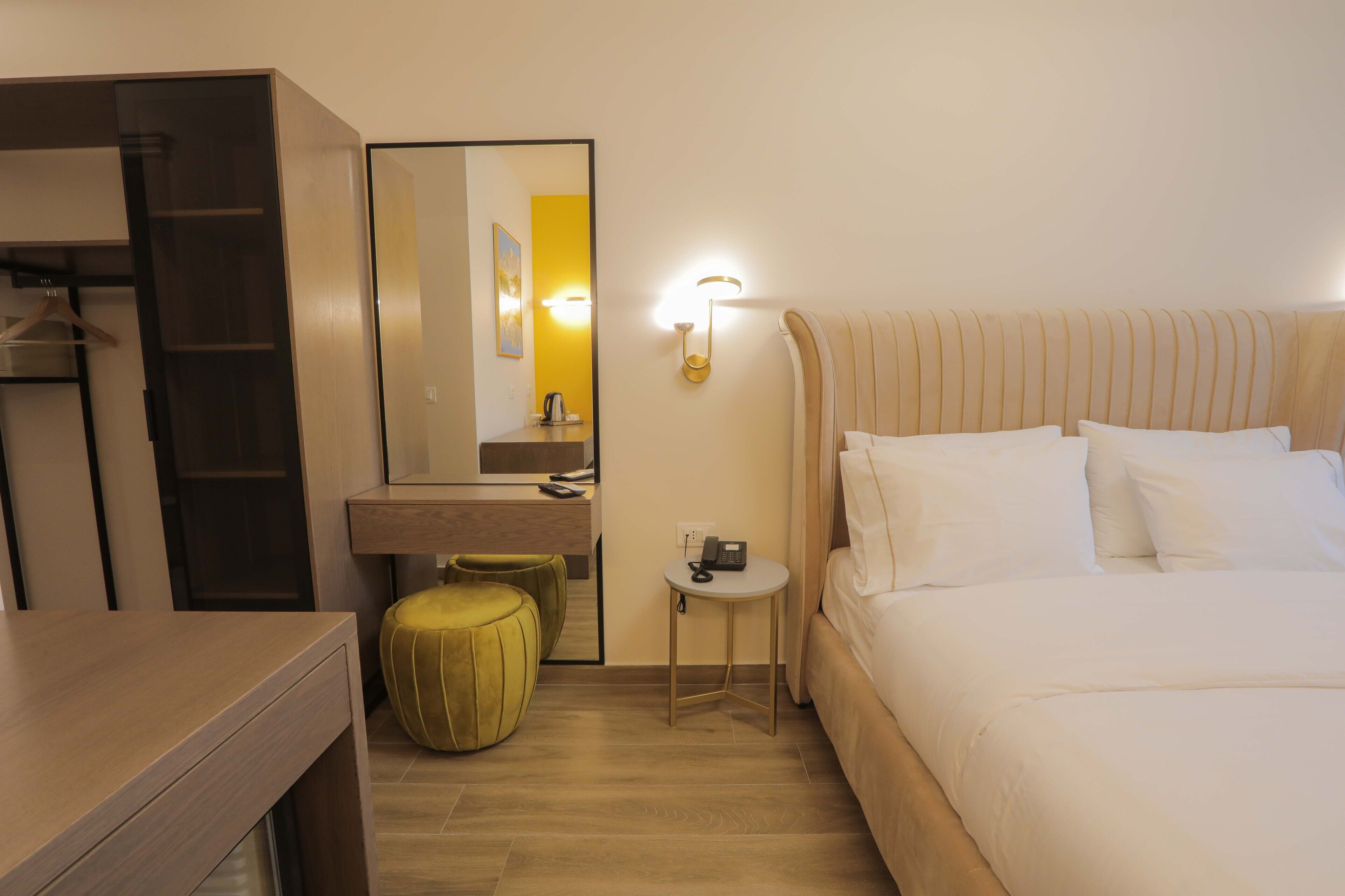 Ein Hotelzimmer mit Bett, Nachttisch, Spiegel, kleinem Tisch mit Telefon und einem Kleiderschrank.