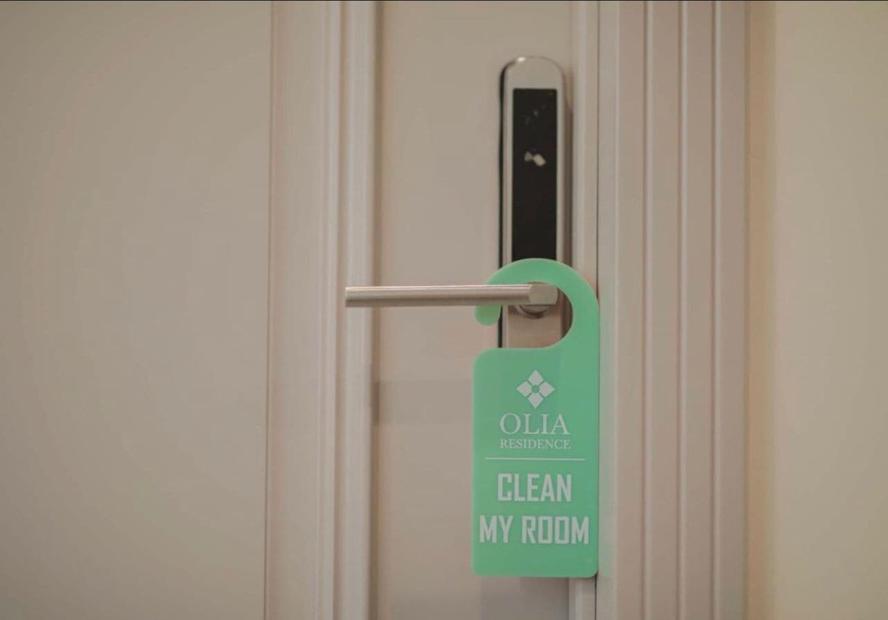 A door with a sign that reads "OLIA RESIDENCE CLEAN MY ROOM".