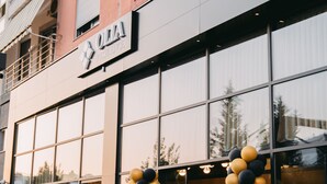 A hotel entrance with a black and gold balloon arch, large windows, and a reception area visible inside. - Olia Residence (Tirana)