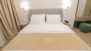 A hotel room with a bed, two bedside lamps, a bedside table with a phone, a green ottoman, and a mirror on the wall. - Olia Residence (Tirana)