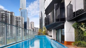 Una piscina en la azotea con vista al horizonte de la ciudad, arquitectura moderna y barandilla de vidrio.