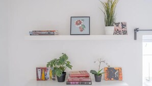 To hvide hylder med bøger, billeder og plantede planter.