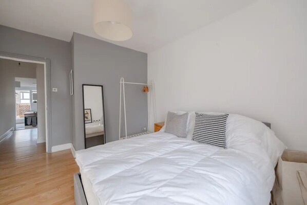 Ein Schlafzimmer mit einem großen Bett, einem Nachttisch, einer Hängeleuchte und einem Spiegel an der Wand.