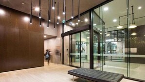 A modern interior with a bench, glass walls, and hanging lights. - Cozy & Modern Studio Right Next to Southern Cross (Melbourne)
