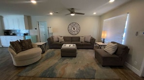 A living room with a sofa set, ottoman, and a wall clock. - Modern Oasis, Pool Heater, BBQ (Phoenix)