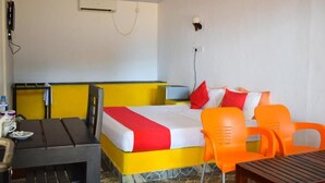 A hotel room with a bed, a desk, and two orange chairs. - Golden Beach Cottages (Trincomalee)