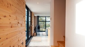 A modern interior with wooden paneling, a large window, and a staircase leading to an upper level.