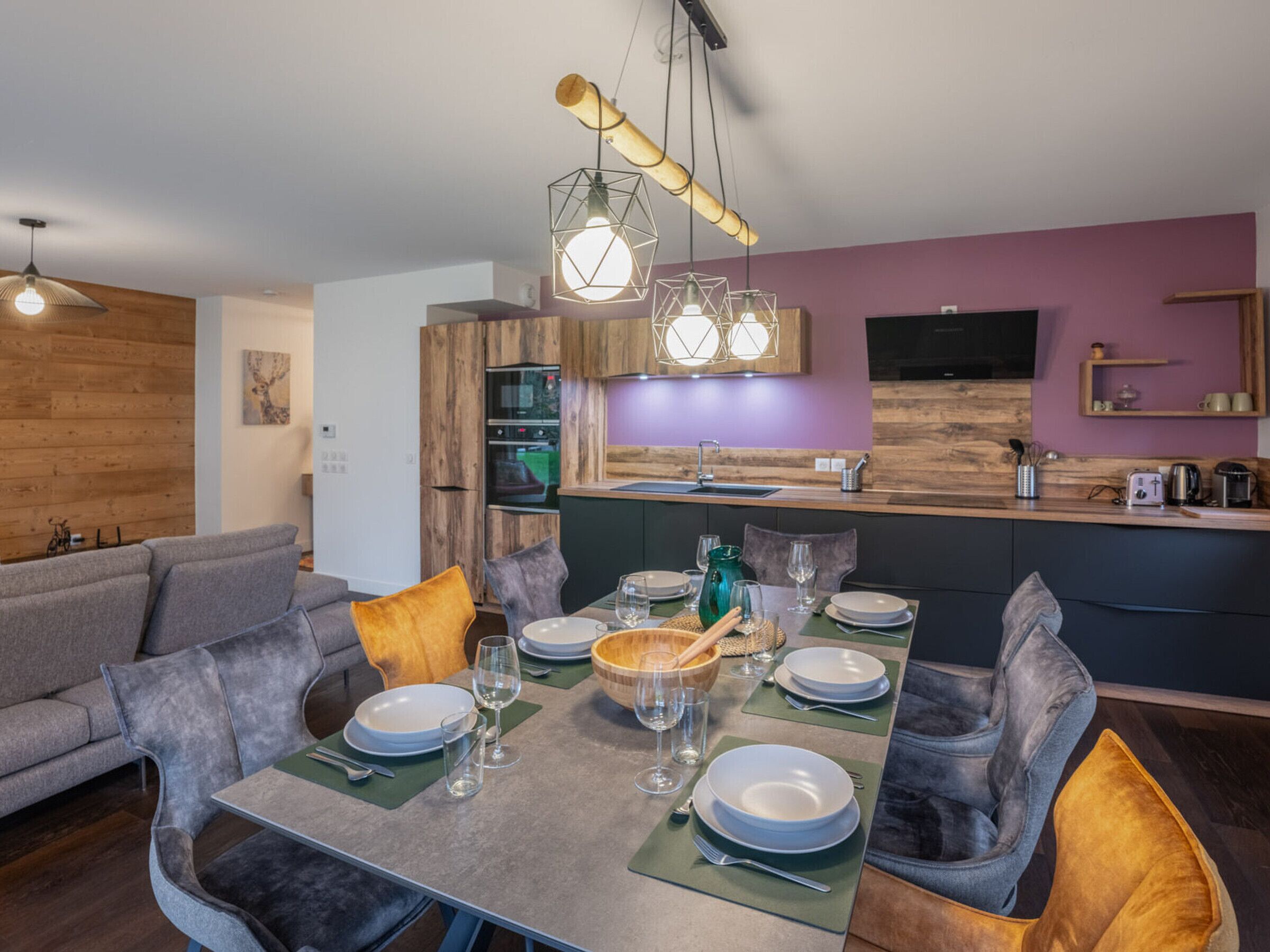 Un espace repas moderne avec une table en bois dressée pour quatre personnes, entourée de chaises à revêtement gris.