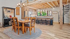 Una cocina amplia con vigas de madera, un comedor con mesa redonda y una barra con taburetes.