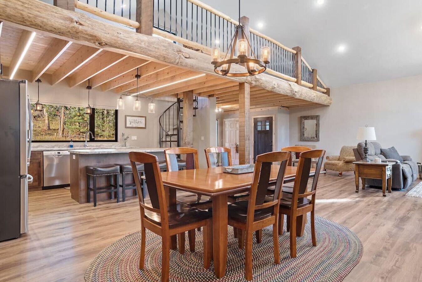 Een ruime keuken met houten balken, een eethoek met een houten tafel en stoelen, en een zithoek met een bank en lamp.