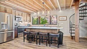Una cocina moderna con vigas de madera, electrodomésticos de acero inoxidable y una zona de bar con taburetes.