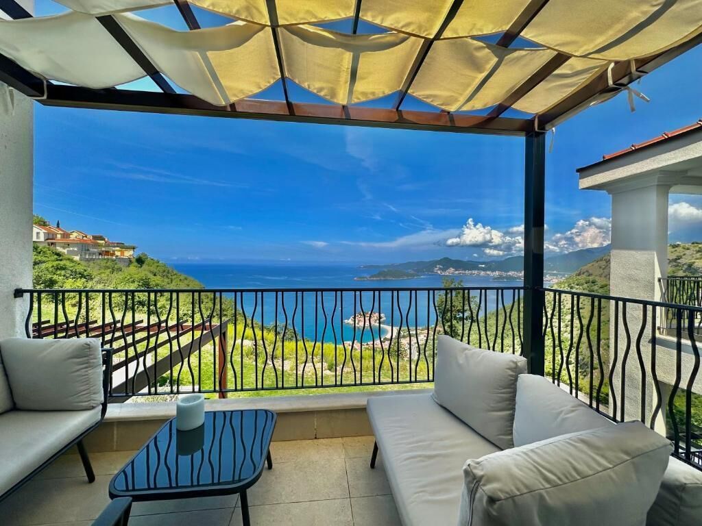 A balcony with a view of the sea, a sofa, and a small table.