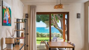A dining area with a view of the sea, a painting on the wall, and a wicker lamp. - Villa with pool, on the sea in Marina di Modica (Marina di Modica)