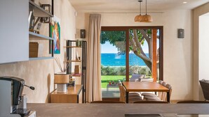 A modern kitchen with a coffee machine, a dining area with a table and chairs, and a view of the ocean through large sliding doors. - Villa with pool, on the sea in Marina di Modica (Marina di Modica)