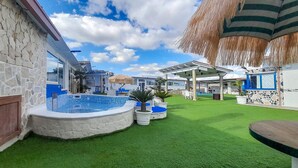 A pool area with a hot tub, artificial grass, and a thatched roof structure. - Awesome apartment in Grottaglie (Grottaglie)