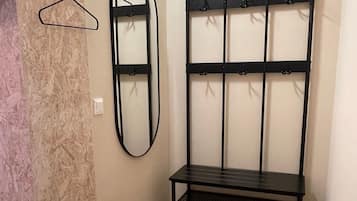 Un corridoio con una panca in metallo nero, uno specchio a parete e un muro con superficie in legno.