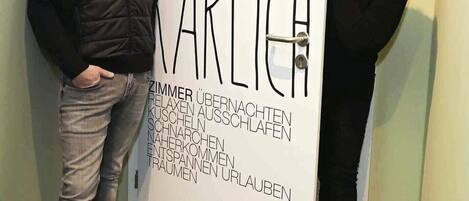 Dos personas de pie frente a una puerta con un letrero que dice "HAUS KARLIEH".